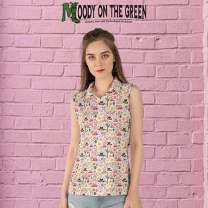 May include: A white sleeveless collared shirt with a colorful pattern of cacti, horseshoes, cowboy hats, and boots. The shirt has a v-neck and is made of a soft, comfortable fabric. The text "MOODY ON THE GREEN" is displayed at the top of the image.