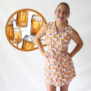 May include: A sleeveless dress with a white background and a repeating pattern of beer mugs. The dress has a collared neckline and a zipper closure. A circular image in the background shows watercolor beer mugs.