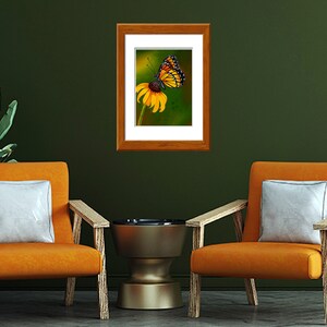 Gouache painting titled 'Flutterby' features a yellow monarch butterfly on a cone flower against a green background. Adds natural elegance to any space.