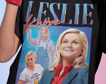 May include: Black t-shirt with a graphic print of Leslie Knope from the TV show Parks and Recreation. The graphic features three images of Leslie Knope in different outfits, including one with the text "I hate Mondays".