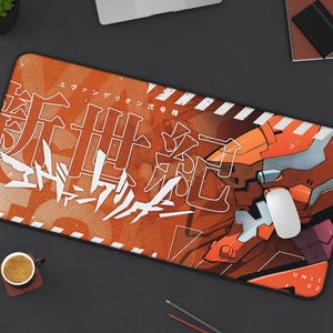 May include: Orange and white mouse mat featuring a large robot illustration and Japanese text. The text reads "エヴァンゲリオン新劇場版:Q". The robot is labelled "UNIT 02".