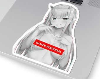 May include: A white sticker featuring an anime-style illustration of a woman with long hair and horns. A red banner across the image reads "WAIFU MATERIAL". The sticker is placed on a laptop.