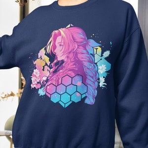 May include: Navy blue sweatshirt featuring a colorful anime-style illustration of a person with pink hair. The design includes a geometric honeycomb pattern and floral accents. The person is also wearing blue shorts.