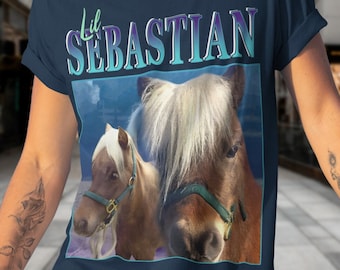 May include: A navy blue t-shirt with the text "Lil Sebastian" printed on the front. The shirt features a picture of two brown and white miniature horses.