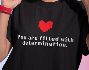 May include: Black t-shirt with a red pixelated heart and the text "You are filled with determination."