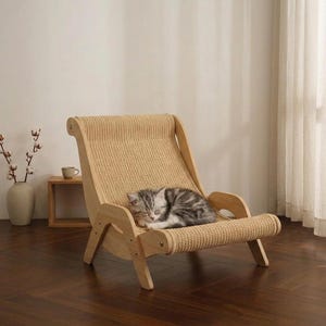 Pode incluir: Uma pequena espreguiçadeira de madeira clara concebida para animais de estimação, com uma estrutura curva e um assento e encosto em tecido de sisal entrançado e texturado. Um gato malhado cinzento e branco dorme enrolado no assento.