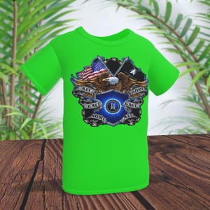 May include: A bright green t-shirt featuring a patriotic design. The graphic includes an American flag, an eagle, and the text "ALL GAVE SOME, SOME GAVE ALL" in a shield shape. The shirt is displayed on a wooden surface.