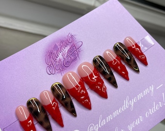 May include: Set of ten red and brown leopard print press-on nails with gold accents. The nails are arranged on a purple card with the text "@glammedbyemmy_ - Thank you for your order!"