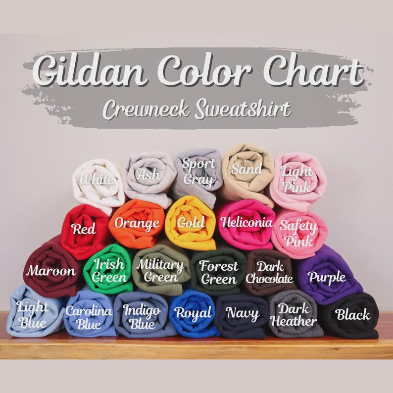 May include: A Gildan Color Chart for crewneck sweatshirts featuring a stacked display of rolled fabric in various colors including white, ash, sport gray, sand, light pink, red, orange, gold, heliconia, safety pink, maroon, green, and black.