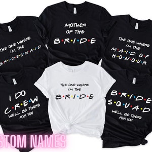 May include: Six black and white t-shirts with a Friends TV show theme. The shirts have different text, including "Mother of the Bride", "The One Where I'm the Bride", "The One Where I'm the Bridesmaid", "The One Where I'm the Maid of Honour", "I Do Crew We'll Be There For You", and "Bride Squad We'll Be There For You".