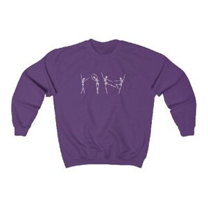 May include: Purple sweatshirt with a white graphic of four skeletons dancing. The skeletons are in various poses, including one holding a hoop.