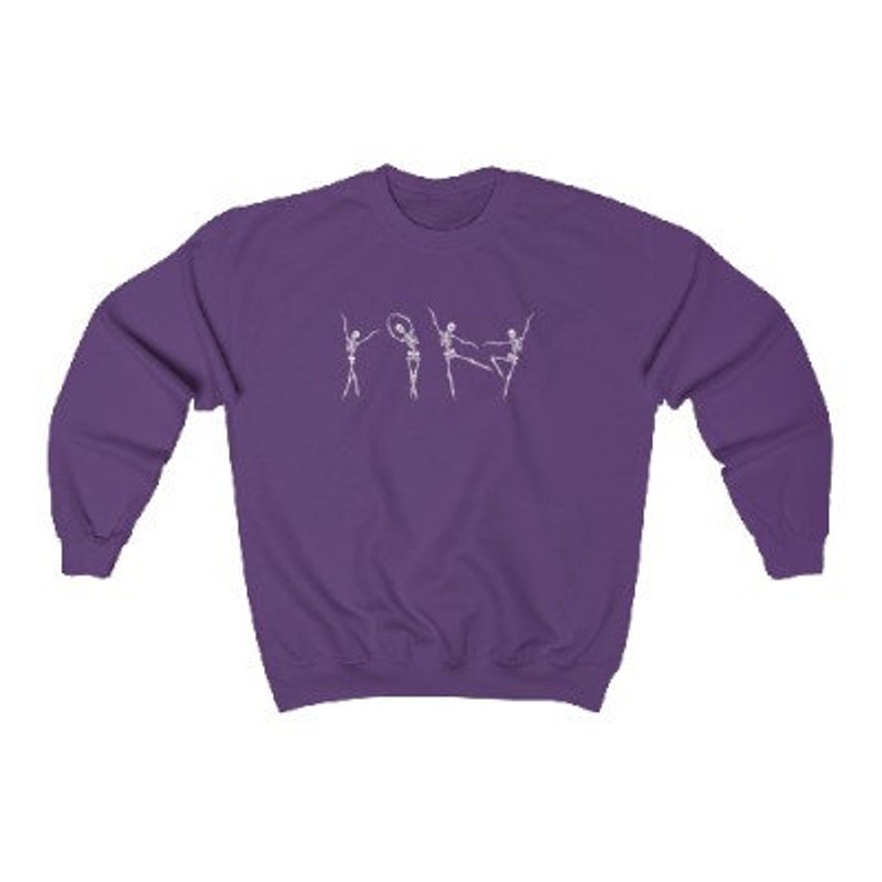 May include: Purple sweatshirt with a white graphic of four skeletons dancing. The skeletons are in various poses, including one holding a hoop.
