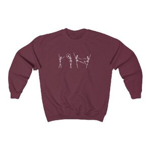 May include: A maroon sweatshirt with a white graphic of five skeletons dancing. The skeletons are in various poses, including one holding a hoop.