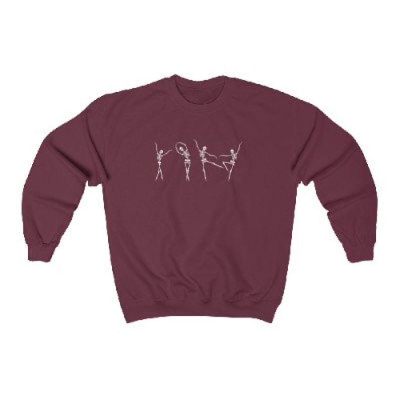 May include: A maroon sweatshirt with a white graphic of five skeletons dancing. The skeletons are in various poses, including one holding a hoop.