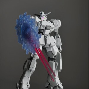 May include: A gray and white model robot figure with a blue shield and red laser beams. The robot has a detailed design with articulated joints and a futuristic aesthetic. The shield has a hexagonal pattern. The robot is standing on a dark surface.