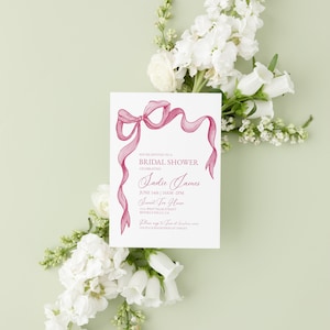 May include: A pink and white bridal shower invitation with a pink ribbon bow and the text "You're invited to a Bridal Shower Celebrating Sadie James June 14th | 10AM-2PM Sunset Tea House 111 West Palm Street Beverly Hills, CA Please RSVP to [email protected] Couple is registered at Target"