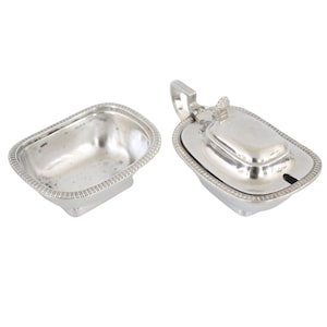 May include: A silver butter dish with a lid and a handle. The dish is oval shaped and has a decorative border.