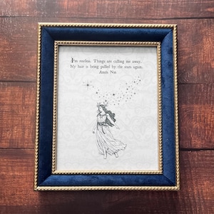May include: A framed print with a drawing of a woman in a flowing dress, wearing a star crown. The print is in a blue velvet and gold frame, with the quote "I'm restless. Things are calling me away. My hair is being pulled by the stars again. Anais Nin."