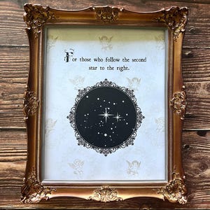 May include: Ornate gold-colored framed print with the text "For those who follow the second star to the right." The print features a black circle with a star constellation design and decorative border on a white background.