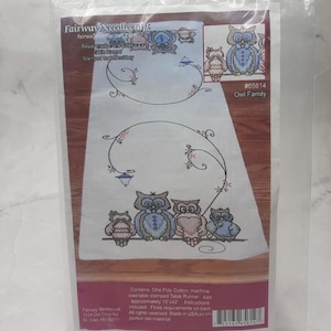 Puede incluir: Un kit de punto de cruz para un camino de mesa con un diseño de familia de búhos. El camino de mesa blanco tiene un patrón estampado de búhos y detalles florales. El paquete dice "Owl Family" y mide aproximadamente 38 x 107 cm.