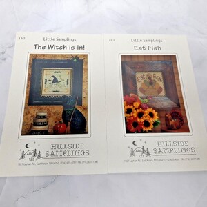 May include: Two cross stitch patterns from Hillside Samplings. The first pattern is titled "The Witch is In!" and features a witch with a black hat and broom. The second pattern is titled "Eat Fish" and features a turkey with the words "Eat Fish" above it.