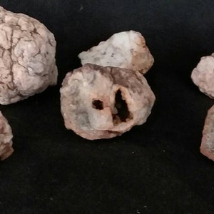 May include: Six pink and brown agate nodules with various crystal formations and cavities. The nodules are rough and have a natural, earthy appearance.