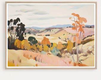 May include: A framed landscape painting depicts rolling hills and trees in shades of yellow, orange, and green. The sky is a pale blue with soft clouds. The artwork has a warm, inviting feel.