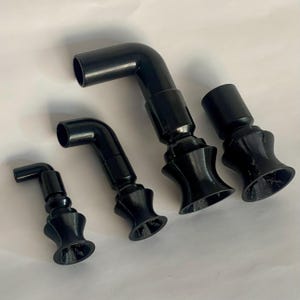 May include: Four black plastic elbow connectors of different sizes are displayed on a white surface. Each connector features a flared base and a right-angle bend. The connectors are new and unused.