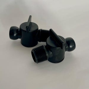 Könnte beinhalten: Zwei schwarze Kunststoffventile mit Griff und Gewindeende. Die Ventile haben einen runden Körper und einen Griff zum Drehen. Die Ventile sind für den Einsatz in Sanitär- oder Bewässerungssystemen konzipiert.