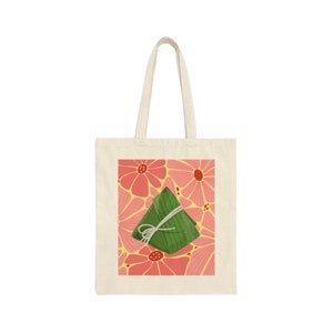 Puede incluir: Una bolsa de tela blanca con una ilustración verde y blanca de un pastel de arroz sobre un fondo floral rosa.