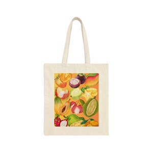 Puede incluir: Una bolsa de tela blanca con un diseño colorido de varias frutas tropicales, incluyendo mangos, carambolas y fruta del dragón, sobre un fondo amarillo.