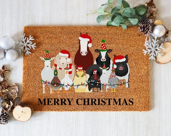 May include: A rectangular coir doormat featuring a festive design with cartoon farm animals wearing Santa hats and party hats. The animals are arranged in a row, with a string of colorful lights. The words "MERRY CHRISTMAS" are printed in black.