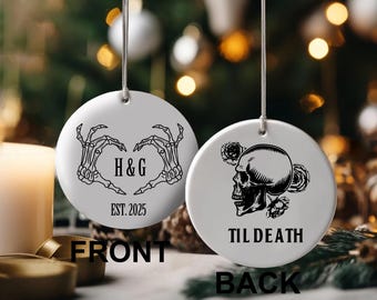 May include: Two white ceramic Christmas ornaments. One features skeleton hands forming a heart with "H&G" and "EST. 2025". The other has a skull with roses and the text "TIL DEATH". Both have a silver string for hanging.