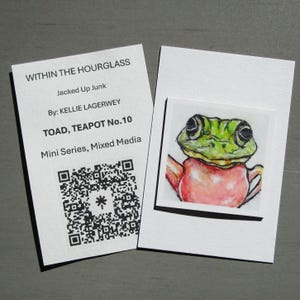 May include: A watercolor painting of a green frog teapot, part of a mini series. The artwork is on a white card next to a card with text that reads "WITHIN THE HOURGLASS" and "TOAD, TEAPOT No.10". The artwork is by Kellie Lagerwey.