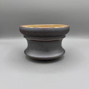 Peut inclure: Un bol en céramique avec un extérieur gris anthracite foncé présentant une texture mouchetée et un bord évasé lisse. L'intérieur du bol est d'une couleur beige clair contrastante, et la base est légèrement effilée avec un profil incurvé.