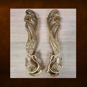 May include: A pair of ornate gold door handles shaped like peacocks with intricate details. The handles are made of solid brass and have a polished finish.