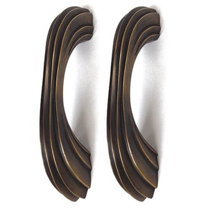 Puede incluir: Dos tiradores de armario de latón antiguo con un diseño curvo y acanalado.