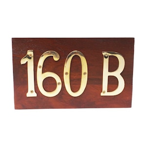 May include: A wooden sign with brass numbers and a letter. The sign reads "160 B".