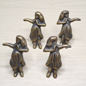 Puede incluir: Cuatro pequeñas figuritas de bronce de mujeres en una pose de baile. Las figuritas están todas mirando en diferentes direcciones y tienen un aspecto ligeramente envejecido, antiguo.