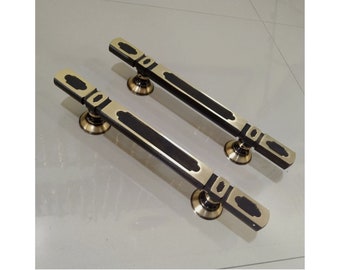 May include: Two black and gold door handles with a decorative design. The handles are made of metal and have a polished finish.
