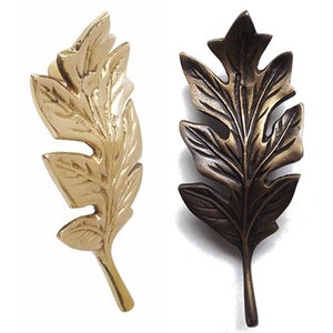 Könnte beinhalten: Zwei dekorative, blattförmige Ornamente aus Metall. Eines ist golden, das andere ist bronzefarben.