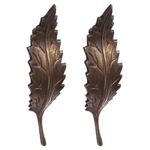 May include: Two antique gold leaf-shaped door pulls with a detailed design.