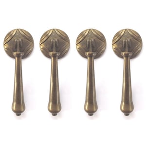 May include: Four antique brass cabinet pulls with a decorative, geometric design. Each pull has a round top and a long, slender stem.