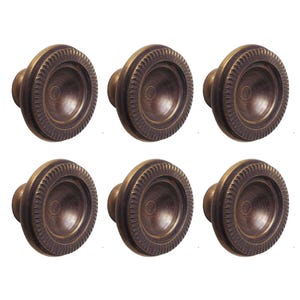 May include: Six antique brass cabinet knobs with a decorative, raised, circular design.