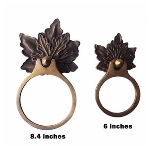 Könnte beinhalten: Zwei antike Türklinken aus Messing mit einem Blattdesign. Die größere Klinke hat einen Durchmesser von 8,4 Zoll und die kleinere Klinke einen Durchmesser von 6 Zoll.