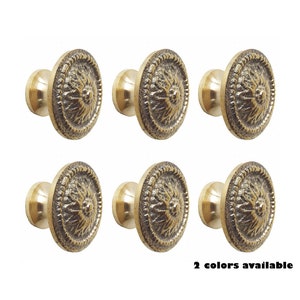 May include: Six gold-toned cabinet knobs with a decorative, raised, sunburst design.  2 colors available.