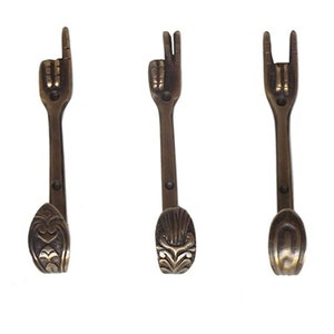 May include: Three brass hooks shaped like hands making different gestures. The hooks are all the same size and have a decorative design at the bottom.