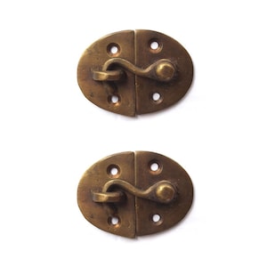 Puede incluir: Dos pestillos de puerta ovalados de latón antiguo con cierre de gancho y ojo. Los pestillos tienen un acabado desgastado y son perfectos para agregar un toque vintage a cualquier proyecto.