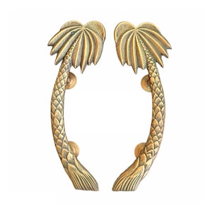 Puede incluir: Un par de tiradores de puerta de palmera dorada. Los tiradores tienen forma de palmeras con un tallo curvo y un diseño de frondas detallado.