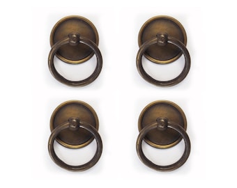 May include: Set of four antique brass ring door pulls. Each pull features a round, flat base with a ring handle.